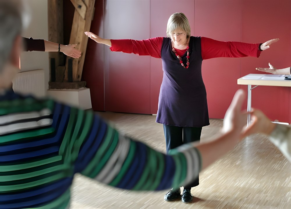 Übung zur Körperwahrnehmung mit ausgebreiteten Armen in einem Seminarraum