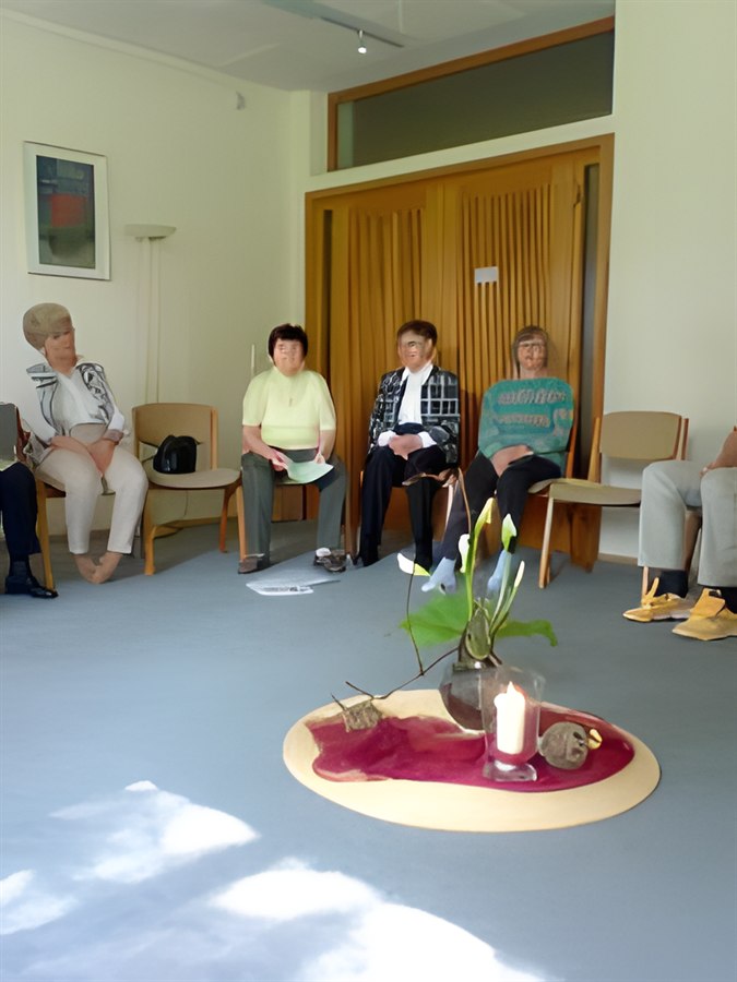Gruppe im Stuhlkreis um eine Kerze und eine Pflanze