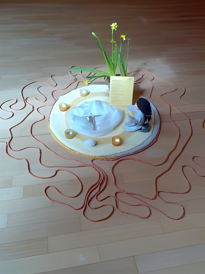 Mandala mit Narzissen und einem roten Faden, der sich über den Boden zieht